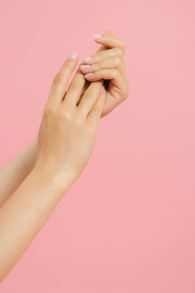 Mains soignées aux ongles nude sur fond rose